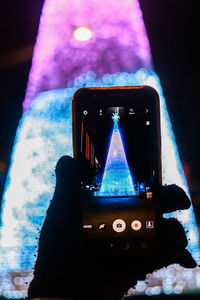 Close-up of hand photographing illuminated smart phone at night