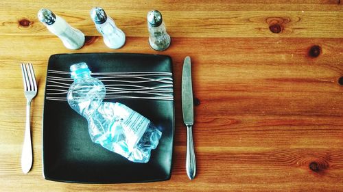 Directly above shot of crumpled bottle in plate on wooden table