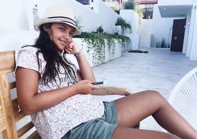 Portrait of smiling girl using mobile phone on porch