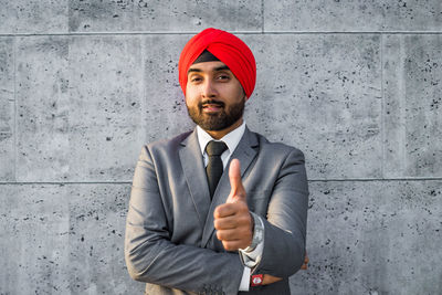 Portrait of smiling businessman wearing turban against wall