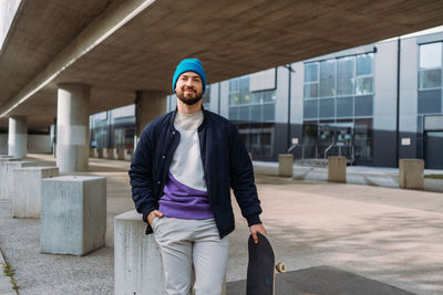 Portrait of young man standing against building