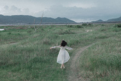 Rear view of woman walking on field