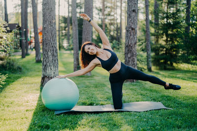 Full length of smiling woman exercising at park