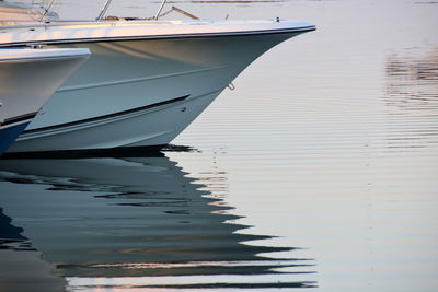 Sailboats moored on sea against sky at sunset