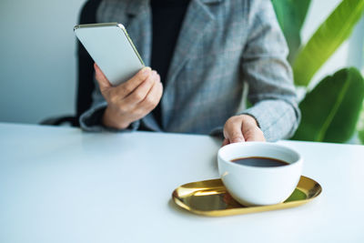 Midsection of woman using mobile phone on table