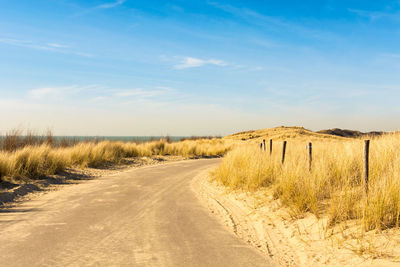 Road amidst sand against sky