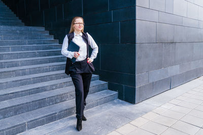 Business caucasian woman holding a laptop and outdoors surrounded by buildings.