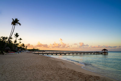 Scenic view of beach against clear sky during sunset