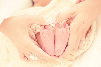 Cropped image of woman holding baby feet