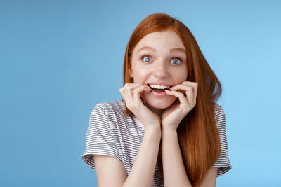 Surprised redhead woman against blue background