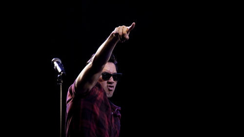 Midsection of person with arms raised against black background