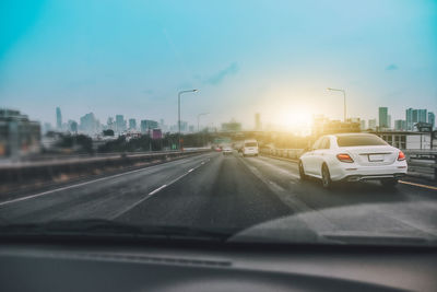 Cars on road against sky seen through car windshield