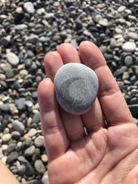 Close-up of hand holding heart shape stone on pebbles