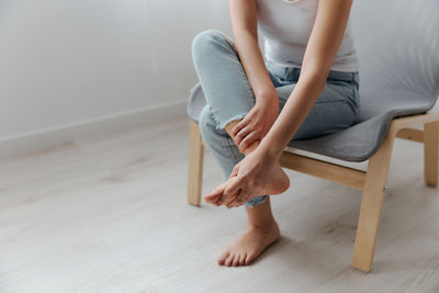 Low section of woman sitting on hardwood floor at home