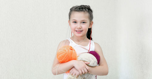 Girl holding wool against wall at home