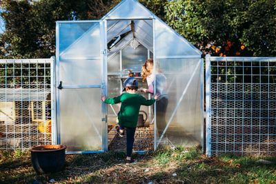 Young brother walking in greenhouse to help sister plant in spring