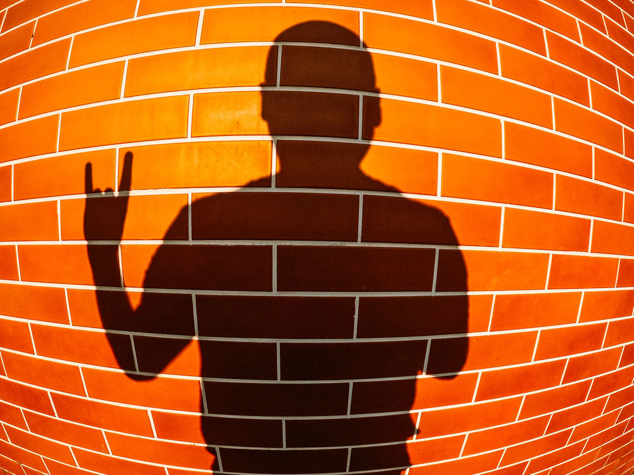 CLOSE-UP OF BRICK WALL WITH ORANGE SHADOW ON TILED FLOOR