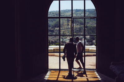 Rear view of man and woman standing by window