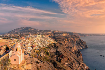 High angle view of buildings by sea against cloudy sky