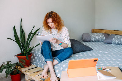 Portrait of young woman using digital tablet while sitting on sofa at home