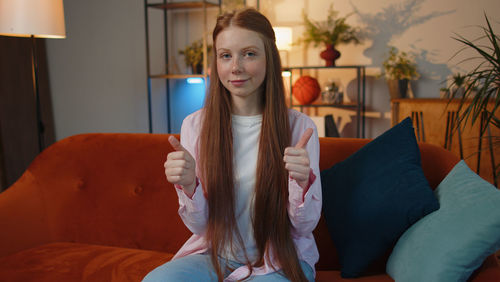 Portrait of young woman sitting on sofa at home