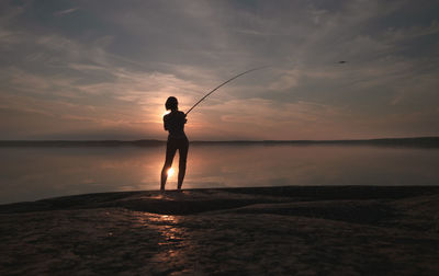 A girl with a fishing rod casts a lure into the lake. back view. scenic atmospheric view. 