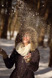 Young woman throwing snow on field