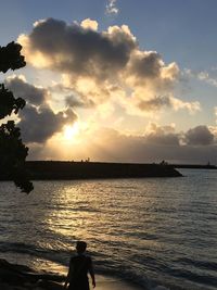 Silhouette woman standing by sea against sky during sunset