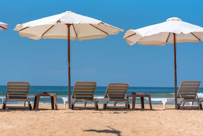 Empty chairs on beach against clear sky