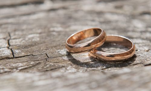 Close-up of wedding rings on old wooden table during sunny day