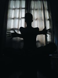 Rear view of silhouette woman sitting at home