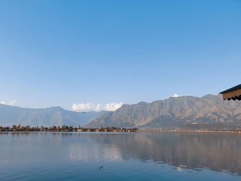 Scenic view of lake and mountains against clear blue sky