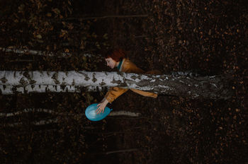 HIGH ANGLE VIEW OF PERSON ON TREE TRUNK