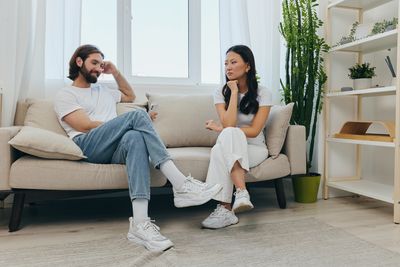 Side view of couple sitting on sofa at home