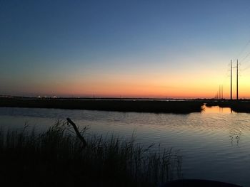 Scenic view of lake against clear sky at sunset