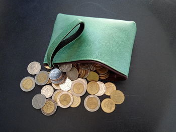 High angle view of coins spilling from purse on table