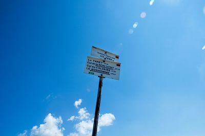Low angle view of sign board against blue sky