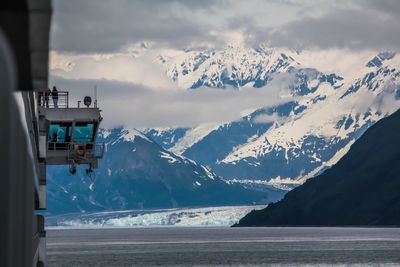 Cropped image ship sailing in sea against snow covered mountains