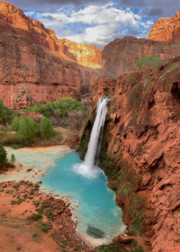 Scenic view of waterfall and turquoise water near grand canyon during golden hour