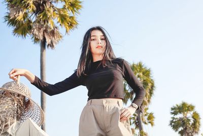 Low angle view of young woman against sky