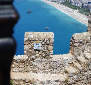 Information sign on retaining wall by sea against sky