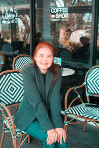 Portrait of smiling woman sitting on chair at restaurant