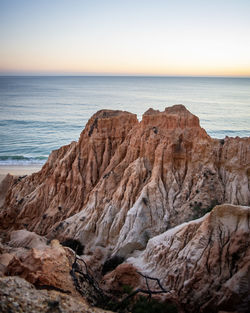 Rock formations on sea shore against sky