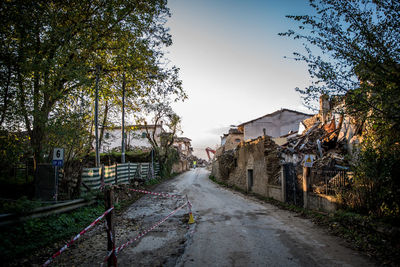 Road amidst trees and buildings against sky