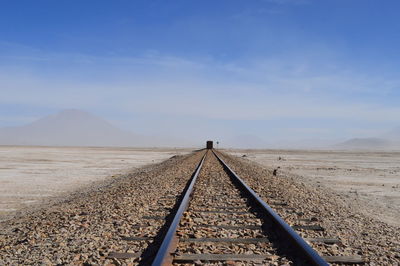 Train on railroad tracks in desert against sky