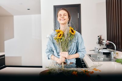 Portrait of young woman using mobile phone while standing at home