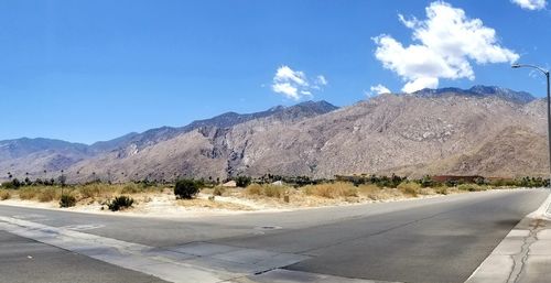 Road by mountains against blue sky