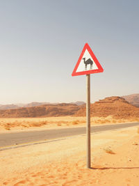 Road sign in desert against clear sky