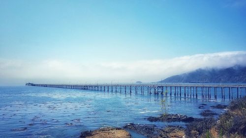 Pier over sea against blue sky