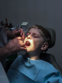 Midsection of male dentist examining boy at hospital